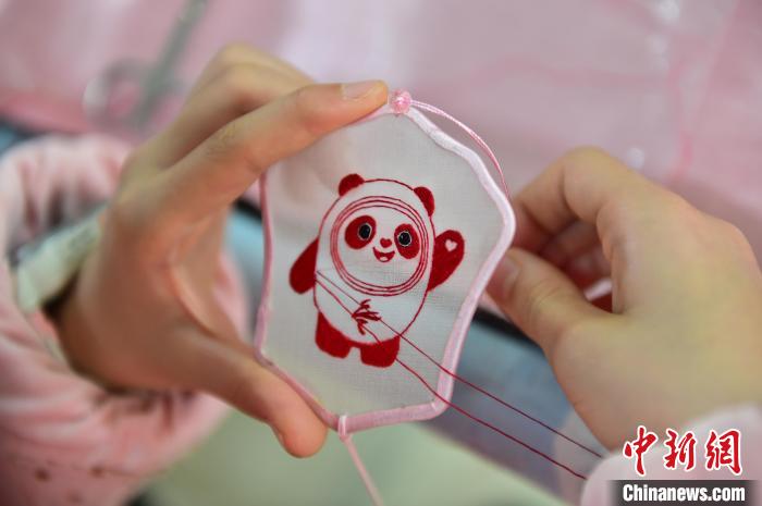 圖為一名小學生正在繡制2022年北京冬奧會吉祥物“冰墩墩”形象?！∮髟屏?攝