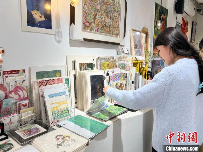 圖為藝術(shù)品商店內(nèi)，顧客挑選插畫作品?！＄婌?攝