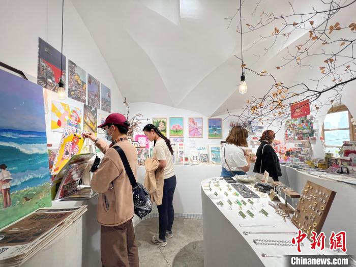 圖為藝術(shù)品商店內(nèi)，顧客挑選插畫作品?！＄婌?攝