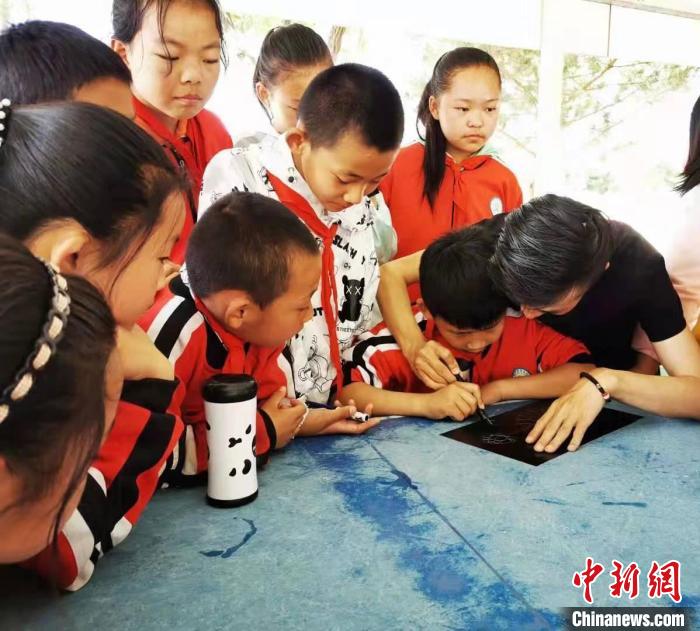 圖為朱增平(右一)教學(xué)生創(chuàng)作鍥金畫(huà)。(資料圖) 受訪者供圖