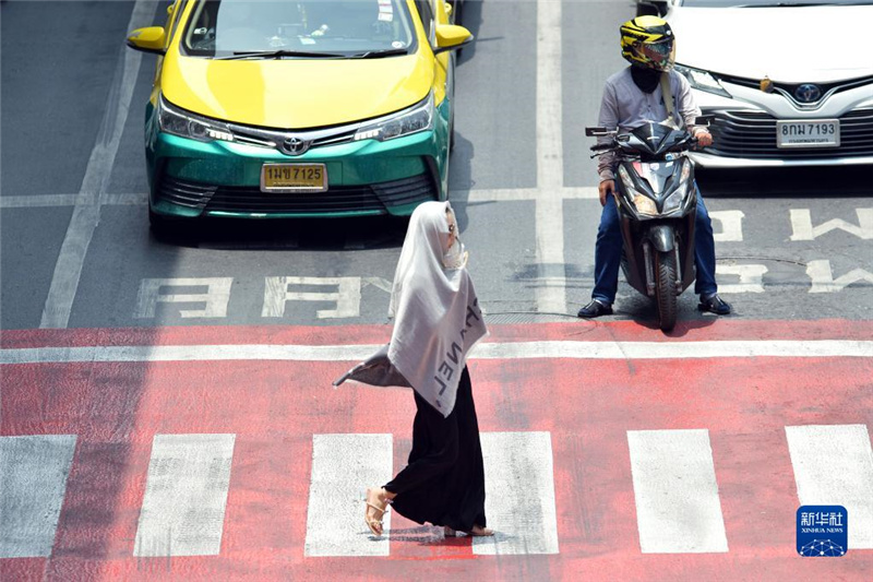 5月17日，行人在泰國曼谷街頭用圍巾遮陽。新華社發(fā)（拉亨攝）