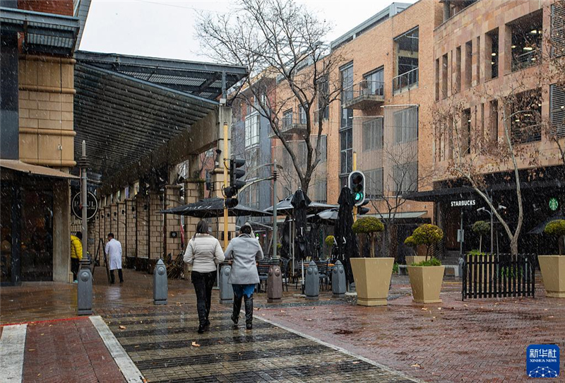 7月10日，在南非約翰內(nèi)斯堡一處商業(yè)區(qū)，人們在雪中行走。新華社記者 張譽東 攝