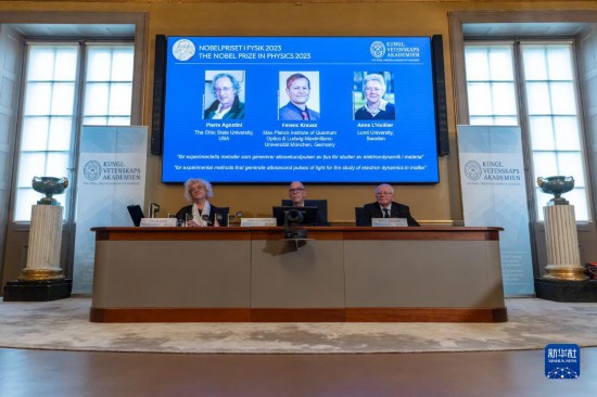 10月3日，在瑞典斯德哥爾摩舉行的2023年諾貝爾物理學(xué)獎公布現(xiàn)場，屏幕上顯示獎項(xiàng)得主皮埃爾·阿戈斯蒂尼（左）、費(fèi)倫茨·克勞斯（中）和安妮·呂利耶的照片。新華社發(fā)（魏學(xué)超攝）