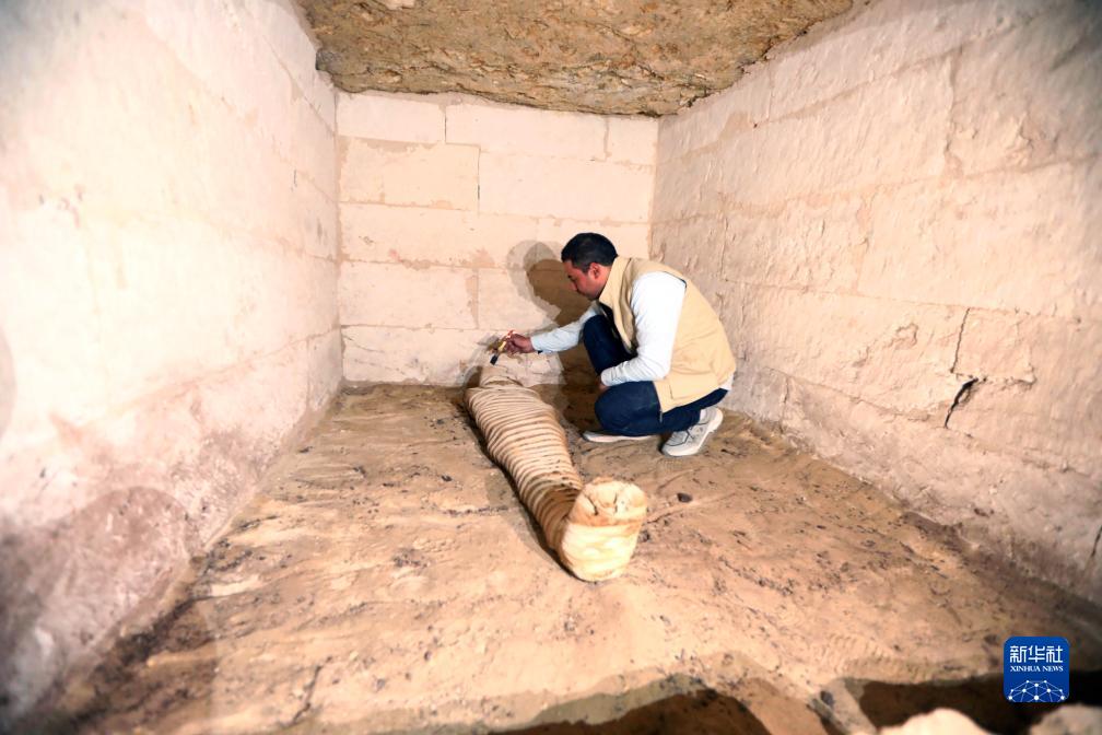 10月15日，在埃及明亞省考古現(xiàn)場，考古人員清理一座石鑿墓中的木乃伊。新華社發(fā)（艾哈邁德·戈馬攝）