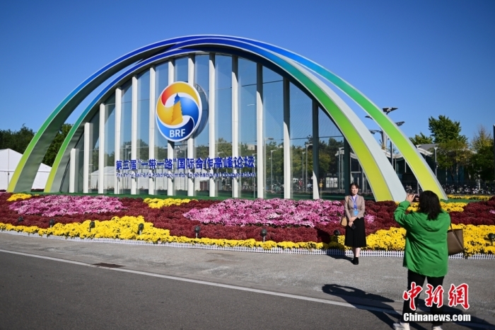 10月15日，北京，工作人員在國家會議中心外的第三屆“一帶一路”國際合作高峰論壇景觀布置前拍照留念。當(dāng)日，位于國家會議中心的第三屆“一帶一路”國際合作高峰論壇新聞中心啟動試運(yùn)行。據(jù)悉，第三屆“一帶一路”國際合作高峰論壇將于10月17日至18日在北京舉行。<a target='_blank' href='/'><p  align=