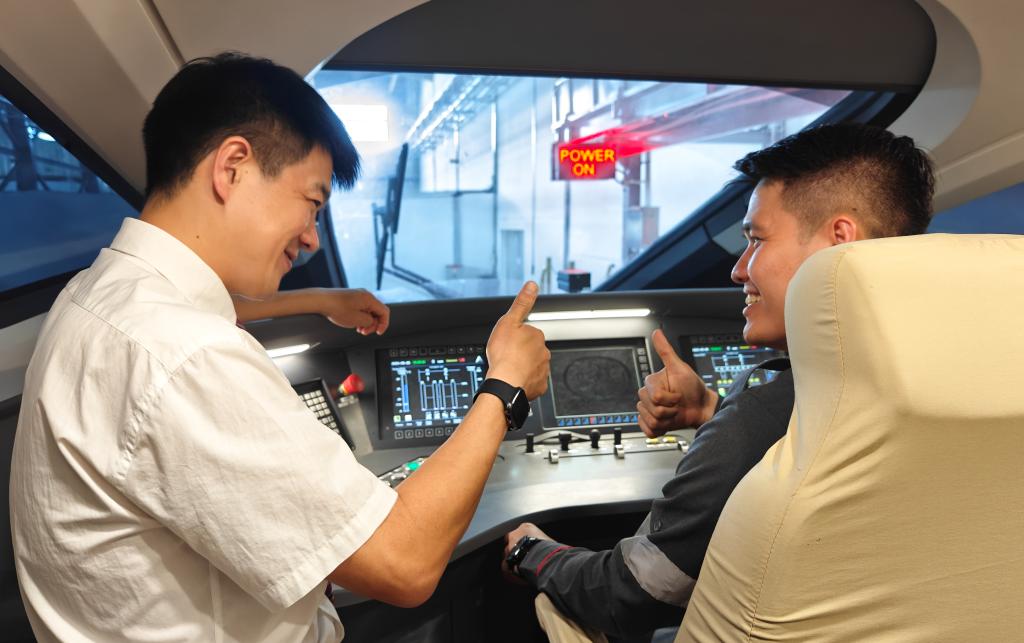 8月25日，在印度尼西亞萬隆的雅萬高鐵德卡魯爾動車所內(nèi)，中國師傅穆振（左）在向印尼火車司機塞蒂亞萬講解動車組出庫前的上電作業(yè)。