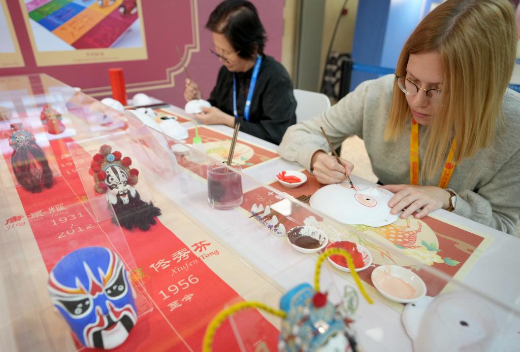 10月16日，在第三屆“一帶一路”國(guó)際合作高峰論壇新聞中心，來(lái)自比利時(shí)的記者（右）體驗(yàn)畫(huà)京劇臉譜。新華社記者 王毓國(guó) 攝