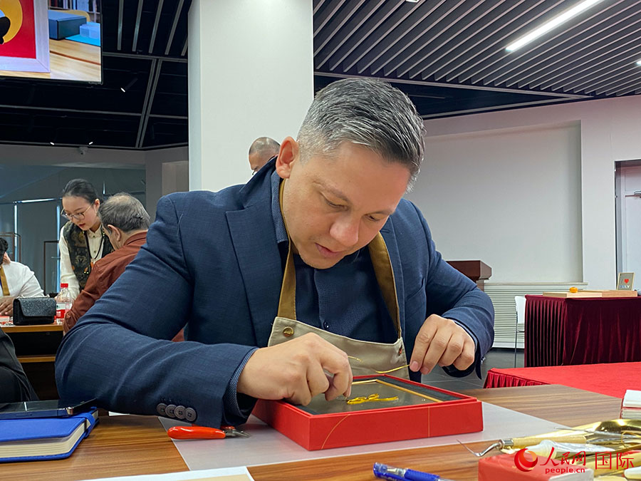 2023“一帶一路”媒體合作論壇聯(lián)合采訪團團員，親身體驗景泰藍工藝。人民網記者 于洋攝