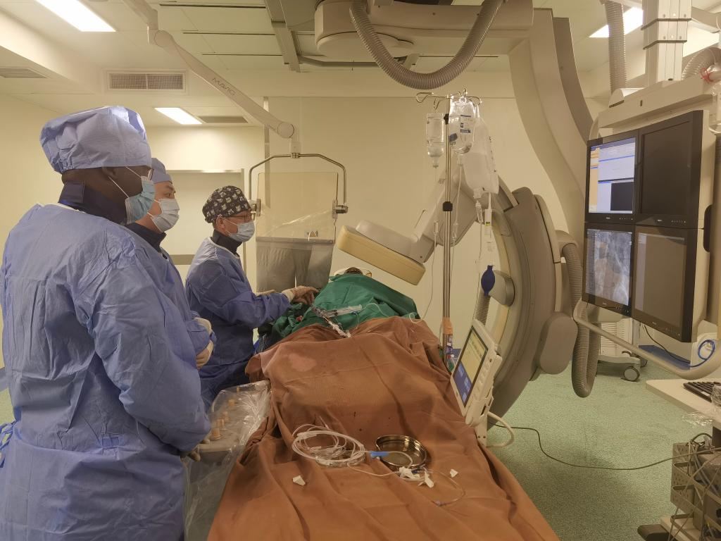 中國第29批援幾內亞醫(yī)療隊隊員、首都醫(yī)科大學附屬北京天壇醫(yī)院心內科副主任醫(yī)師王汝朋（右一）正在給患者做手術。（北京天壇醫(yī)院供圖）
