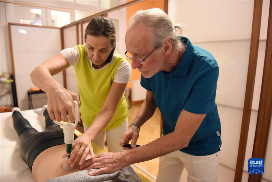 12月12日，在奧地利維也納，科格勒醫(yī)生（右）和助手在為病人進行拔罐治療。新華社記者 賀燦鈴 攝