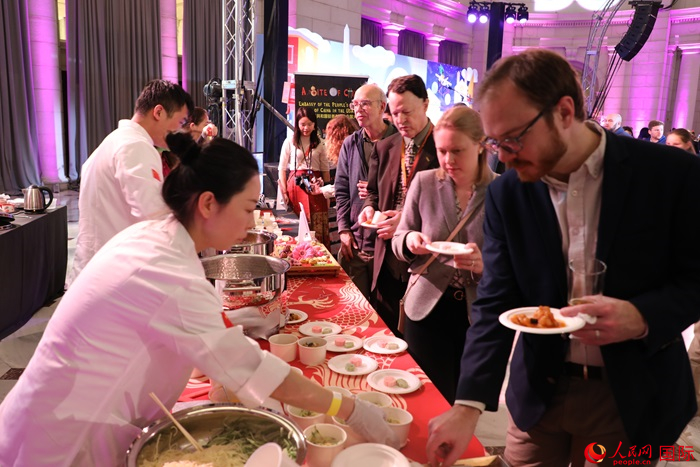 當(dāng)?shù)貢r間3月7日晚，華盛頓聯(lián)合車站廣場舉行駐美使團(tuán)“使館主廚挑戰(zhàn)賽”。圖為當(dāng)?shù)孛癖娫谥袊古_前體驗中國美食。人民網(wǎng)記者 李志偉攝