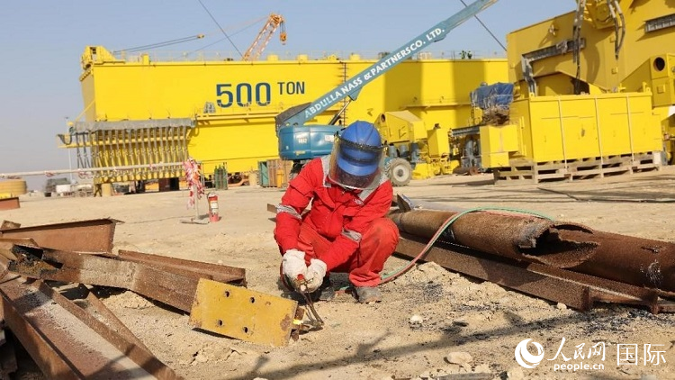 工人正在龍門吊吊裝現(xiàn)場切割金屬件。人民網(wǎng)記者管克江攝