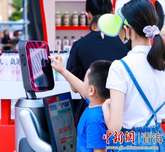 圖為一名小朋友正在和機(jī)器人“志愿者”進(jìn)行互動。 沐聞 攝