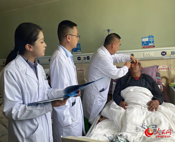 董光明（左三）帶領(lǐng)醫(yī)生對(duì)患者進(jìn)行術(shù)前檢查。人民網(wǎng)記者 杜燕飛攝