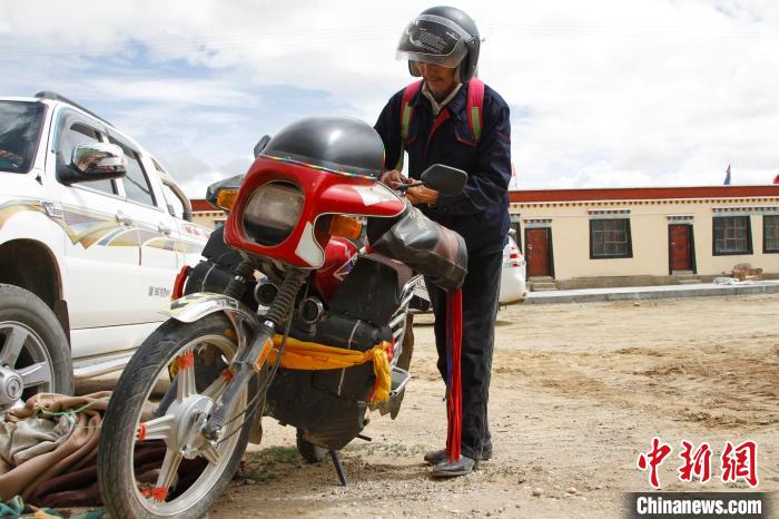 圖為白瑪準(zhǔn)備騎摩托車巡湖?！≮w朗 攝