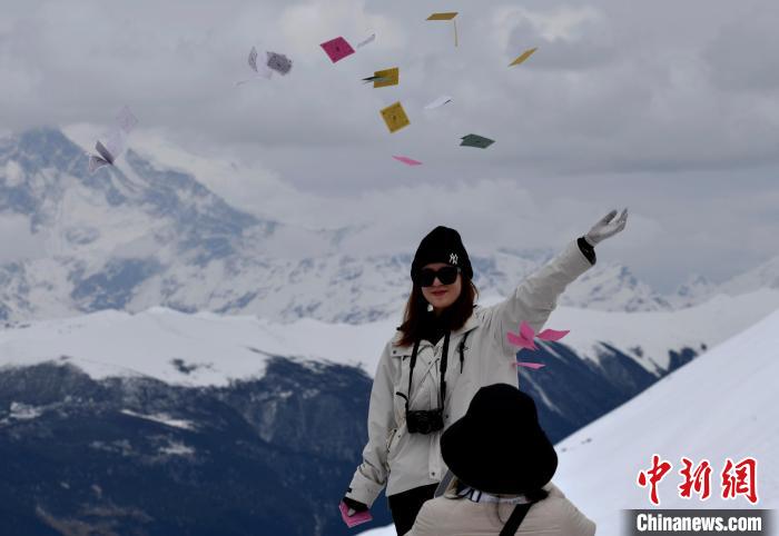 圖為5月14日，游客在西藏林芝色季拉山觀景臺拋灑“隆達(dá)”(風(fēng)馬旗，藏族民眾的一種祈福方式)?！±盍?攝
