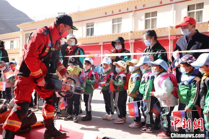 圖為消防指戰(zhàn)員為學(xué)生講解、演示先進救援裝備?！≮w琳 攝