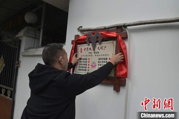 桂溪鎮(zhèn)渭溝村政府工作人員為“十星級文明戶”掛上牌匾。　楊勇 攝