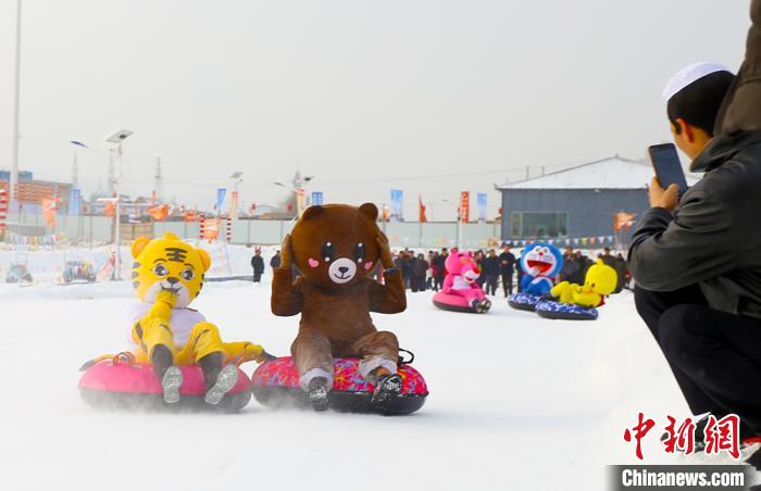 圖為臨夏市南龍鎮(zhèn)馬家莊村舉辦的鄉(xiāng)村文化旅游節(jié)上，游客穿著卡通服裝在體驗(yàn)雪上飛碟項(xiàng)目。近年來(lái)，臨夏州形成了“春賞花、夏避暑、秋摘果、冬玩雪”的全季節(jié)旅游產(chǎn)品體系。(資料圖) 高展 攝