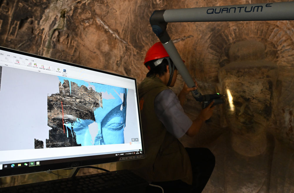 2025年4月9日，武漢大學(xué)文化遺產(chǎn)智能計算實驗室團隊成員在魏字洞使用關(guān)節(jié)臂掃描儀對佛像進行數(shù)字化掃描。圖片來源新華社