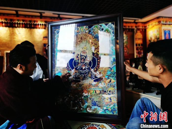 圖為久美尖措(左)與徒弟們展示唐卡作品?！?zhí)砀?攝