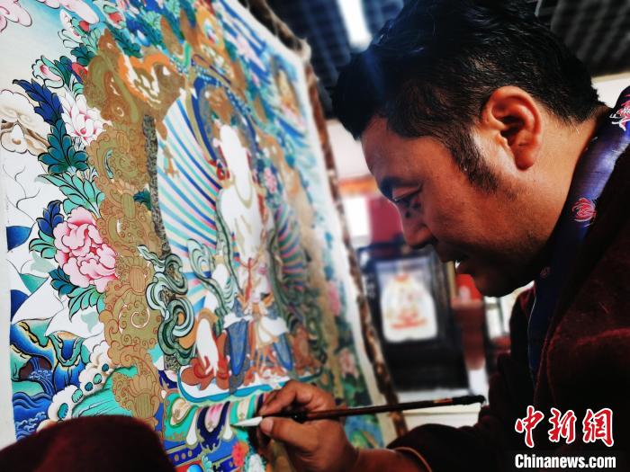 圖為久美尖措創(chuàng)作唐卡?！?zhí)砀?攝