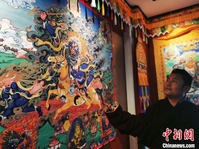 圖為久美尖措展示唐卡作品?！?zhí)砀?攝