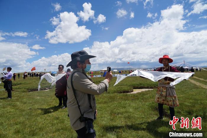 圖為一名外籍?dāng)z影師記錄當(dāng)?shù)夭刈鍤g迎儀式。　馬銘言 攝