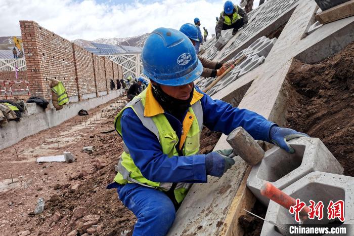 圖為光伏發(fā)電項目施工區(qū)工人在護(hù)坡鋪設(shè)空心磚?！±铍h 攝