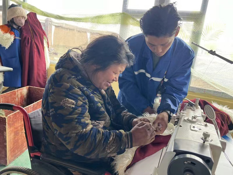 扎西奪爾登幫助殘疾員工裁剪。阿壩州文明辦供圖