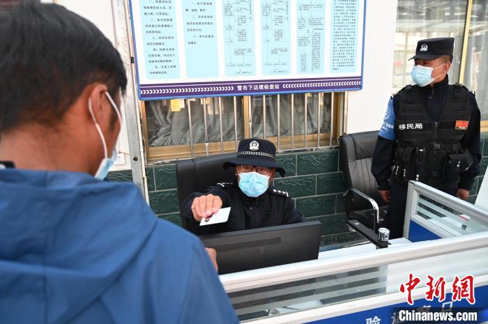 圖為移民管理警察登記完身份信息后將證件歸還給行人?！≮w朗 攝