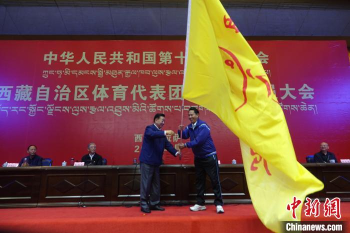 西藏自治區(qū)副主席甲熱·洛桑丹增授代表團(tuán)團(tuán)旗，西藏自治區(qū)體育局局長尼瑪次仁接旗?！∪轿木?攝
