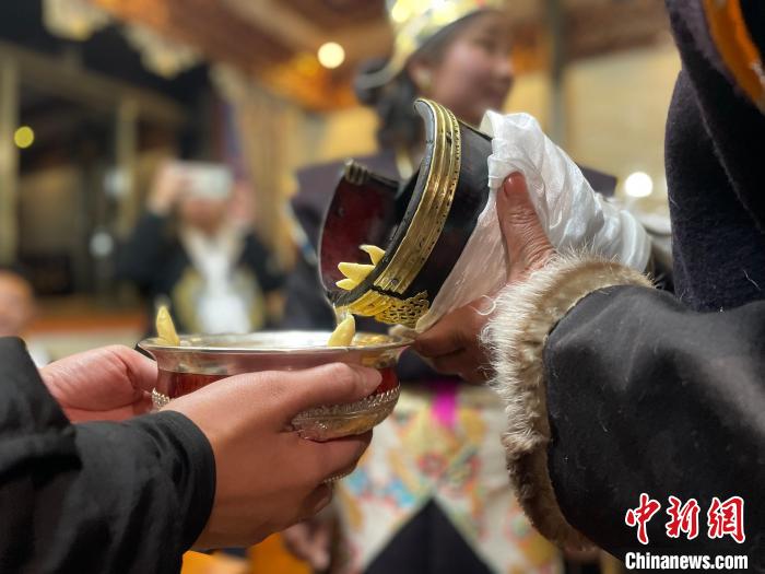 圖為主人在碗中斟滿青稞酒?！∪轿木?攝