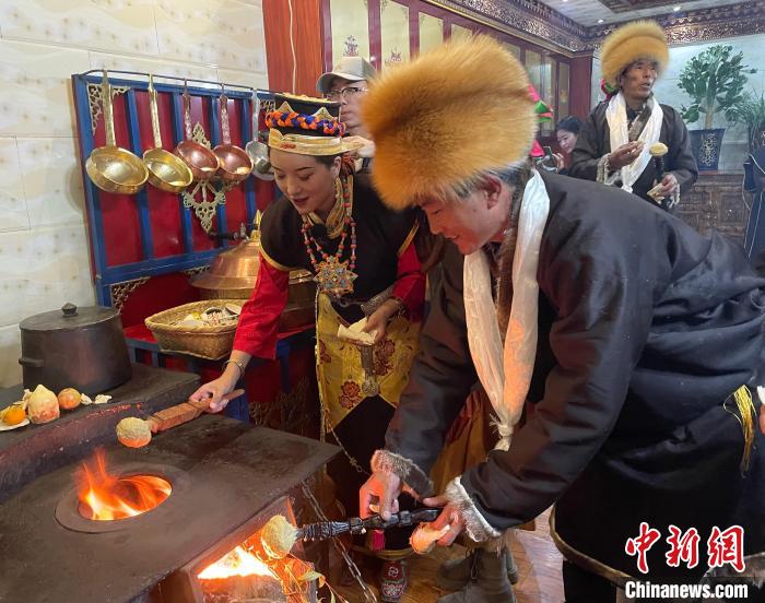 圖為人們在火上烤節(jié)日美食“結(jié)達”?！∪轿木?攝