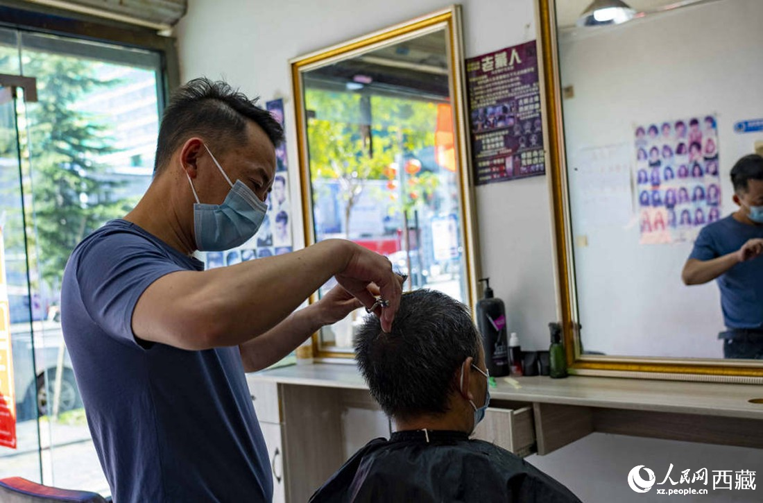 理發(fā)店老板為顧客理發(fā)。次仁羅布 攝