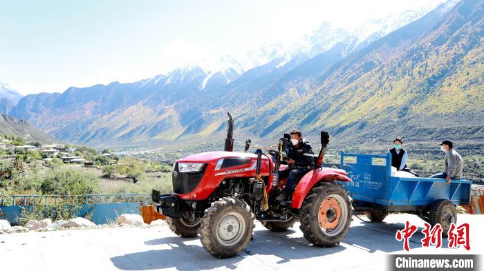 圖為工作人員將把加工完成的糌粑運(yùn)送至村民手中?！〖卫杩h融媒體中心供圖