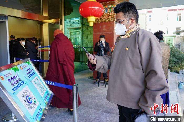 圖為政協(xié)委員掃場所碼進入會場?！〗w波 攝