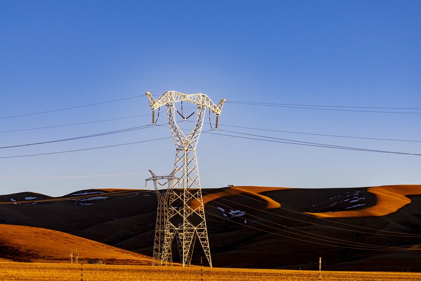 阿里地區(qū)的曠野上，電力鐵塔在夕陽下熠熠生輝。
