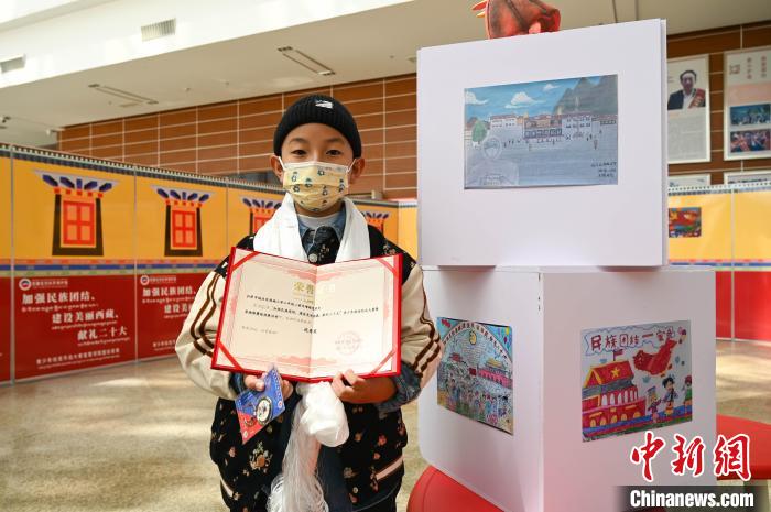 圖為一名獲獎(jiǎng)學(xué)生與自己的繪畫(huà)作品合影?！≮w朗 攝