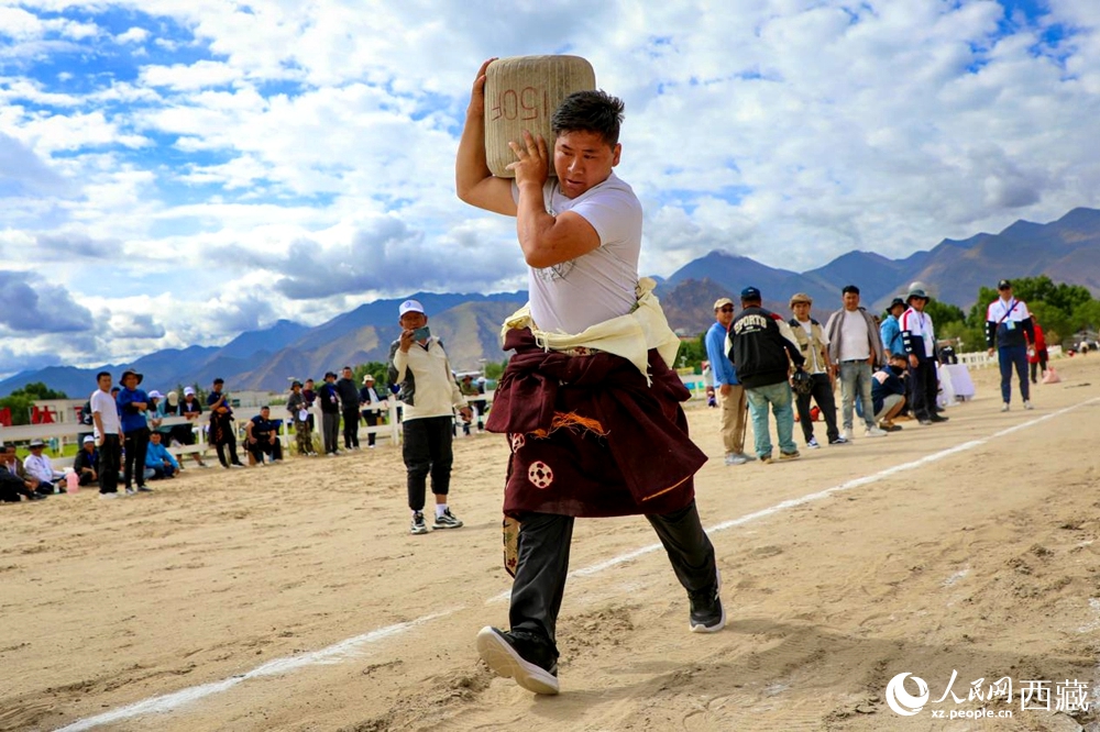 來(lái)自拉薩市當(dāng)雄縣的牧民選手將一塊150斤重的石頭扛在肩上飛奔。